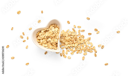Tableau sur toile A heart-shaped white bowl brimming with rolled oats, with additional oat flakes