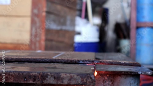 Industrial gas cutting torch melting through a steel plate with bright flames and golden sparks flying out during fabrication.