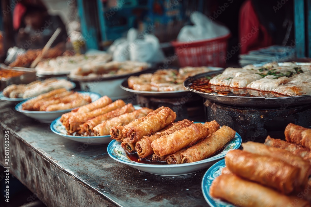 Obraz premium Golden fried spring rolls and savory flatbreads arranged on a market stall