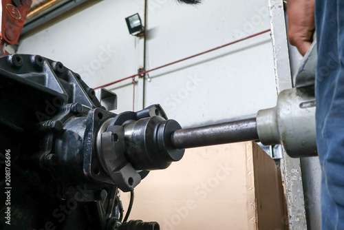 Valokuva Close up of a technician using a heavy-duty pneumatic impact wrench to loosen or tighten the main shaft nut on a large industrial transmission gearbox flange