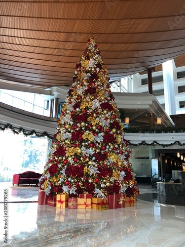 Large decorated Christmas tree in a hotel lobby with gifts underneath.