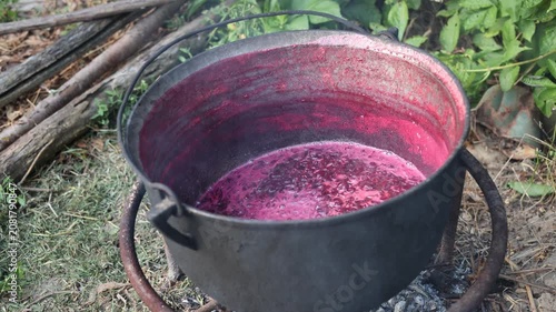 Cooking berry jam in a large cauldron over an open fire outdoors