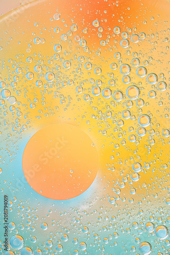 Vertical macro image of tiny air bubbles in liquid with warm yellow and orange tones blending into soft blue. Clean abstract texture for cosmetic, scientific