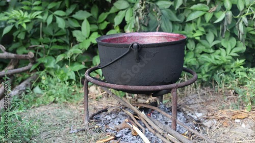 Cooking berry jam in a large cauldron over an open fire outdoors