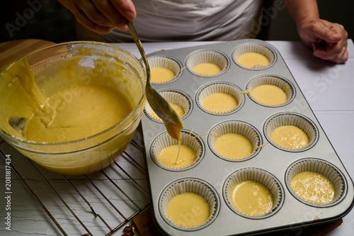 Konstfotografi Hand pours golden custard into paper cups