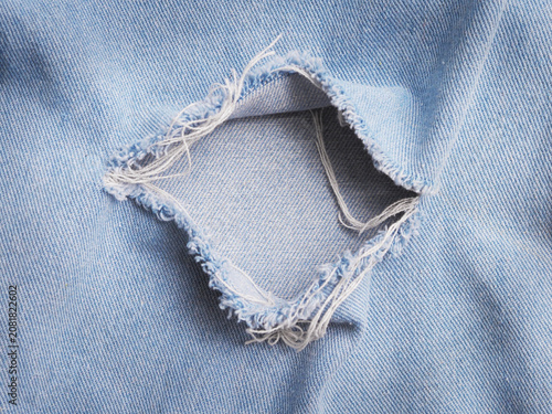 ripped torn pattern of light blue denim jeans texture