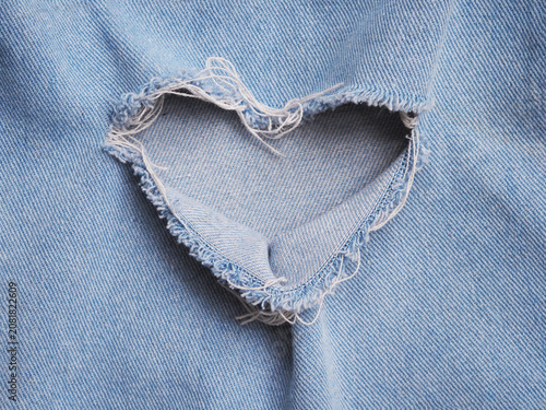 Heart shape ripped jean denim texture background.