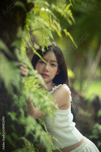 A beautiful young woman among the fern leaves in the forest.