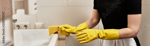Фотография A hotel maid diligently wipes down the sink and countertop in her kitchen, showcasing her focus