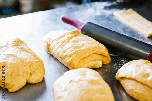 Obraz na płótnie Professional baker folding and shaping sourdough dough on a floured stainless steel work surface in an artisan bakery