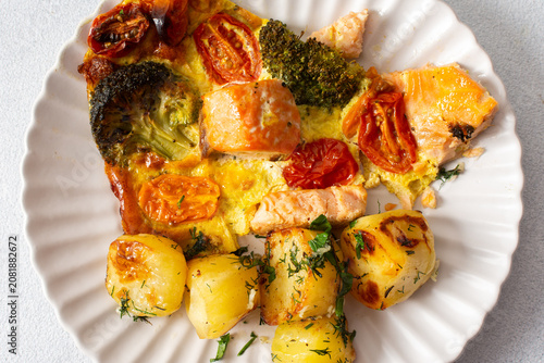 Fotografie Baked potatoes are served with salmon, broccoli, and tomatoes on a plate