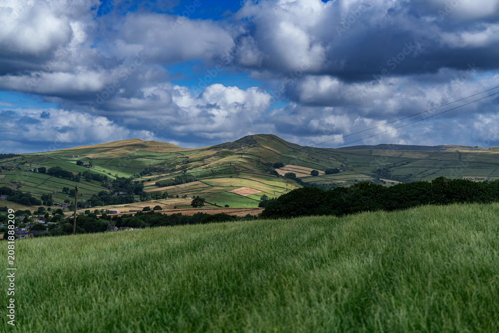 Obraz premium Rolling green hills under dramatic cloudy sky