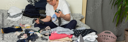 Foto A 52-year-old woman sits on her bed, sorting a pile of laundry