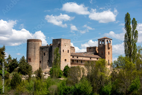 Exterior panoramic view of the medieval and Mudejar style Castle of Castilnovo with its defensive towers and stone walls surrounded by trees in Castilnovo, Segovia, Castile and León, Spain