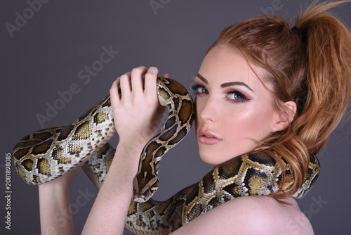 Tableau sur toile Beautiful redhead model girl dressed in a tight, black dress, holding her pet py