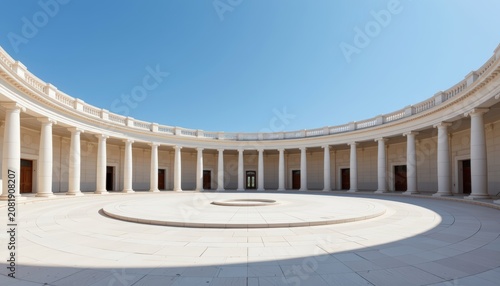 An open circular courtyard surrounded by symmetrical white columns beneath a clear blue sky