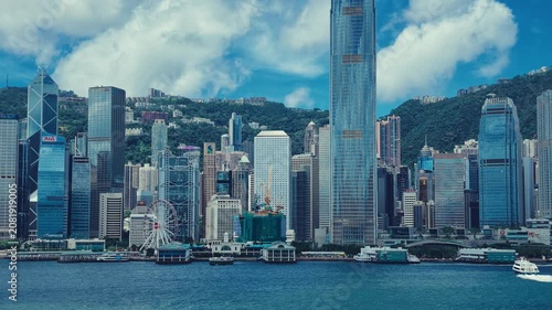 A dynamic view of Hong Kong's iconic skyline against lush green hills.