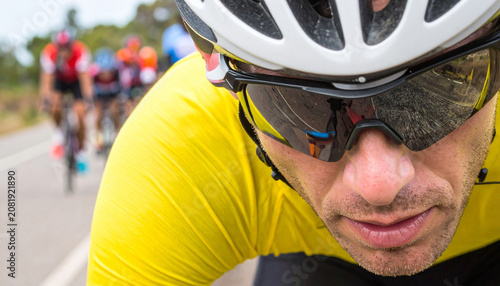 Close up of male cyclist in yellow jersey with road race reflection in sunglasses. Intense professional cycling championship atmosphere