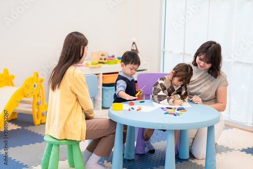 Tableau sur toile Children and adults create art at a colorful table in a playroom during a weekda