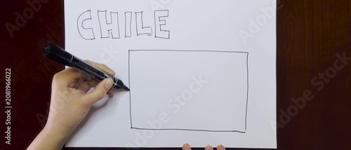 Hands Writing Chile on White Paper with a Black Marker and then Drawing the Chilean Flag, coloring it with blue and red markers on a Wooden brown Table 