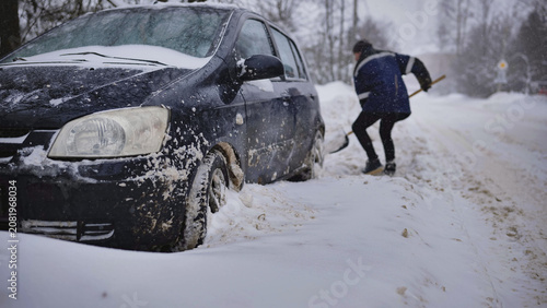 Fotografía Driver shoveling snow from car stuck in deep winter blizzard on street
