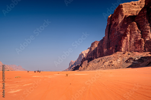 People on horses in wild desert landscape with majestic mountains, Wadi Rum, Jordan.