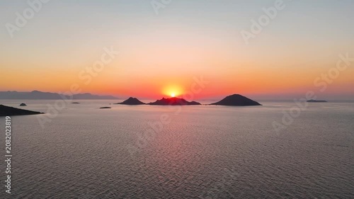 Cinematic aerial drone rising reveal shot over Aegean Sea at sunset with Kadin Adalari islands silhouette during golden hour magic hour Bodrum Turgutreis peninsula Mugla Turkey