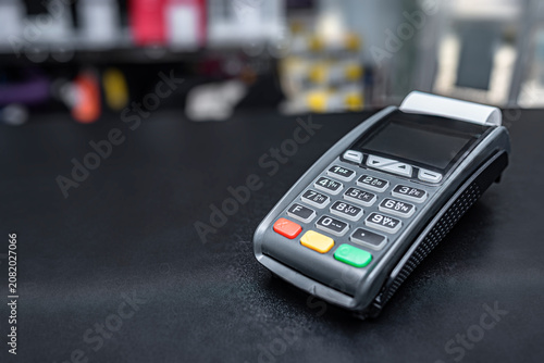 A modern credit card terminal sits on a black counter in a retail store.