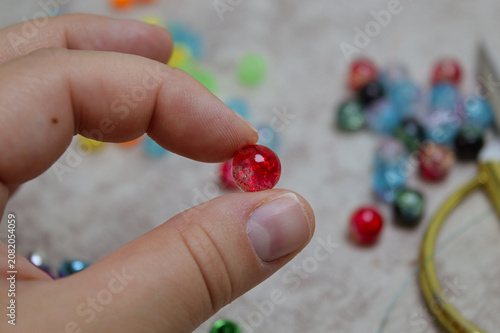 Foto Close-up of a hand holding a single red, textured bead with shimmering highlights