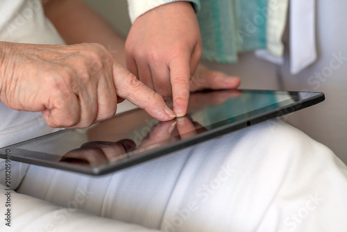 Obraz na płótnie n elderly person and a younger individual use a tablet together