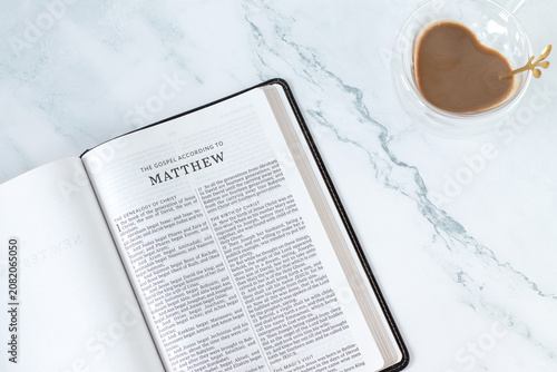 Картината върху платно Matthew gospel in holy bible book with coffee cup on white marble background