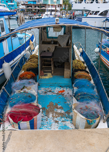 Fishing boat loaded with neatly stacked nets, ready for next voyage in Cyprus. Commercial fishing, maritime industry, Mediterranean harbor, coastal economy and professional fishing concept.