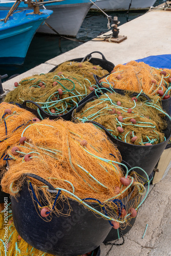 Fishing gear and vibrant nets arranged on quay next to boat in Mediterranean harbor in Cyprus. Nautical industry, waterfront activity and local fishing concept.