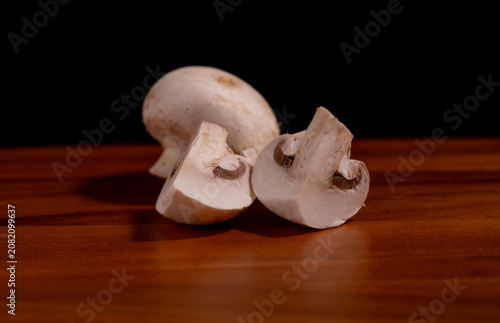 Fresh white button mushrooms (champignon mushrooms) arranged on a wooden cutting board. Natural organic ingredients for healthy cooking, meal preparation, vegetarian recipes.