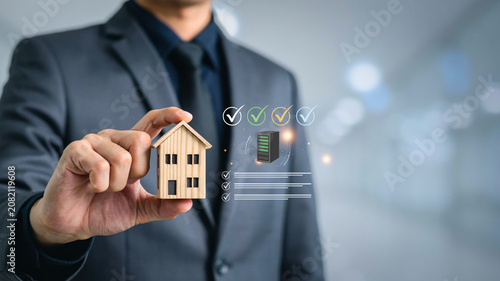 Real Estate Agent Holding a Miniature House, Symbolizing Home Ownership and Property Investment