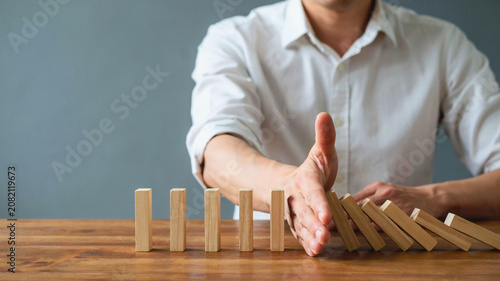 Businessman Hand Stopping Falling Wooden Blocks Concept for Risk Management and Business Intervention