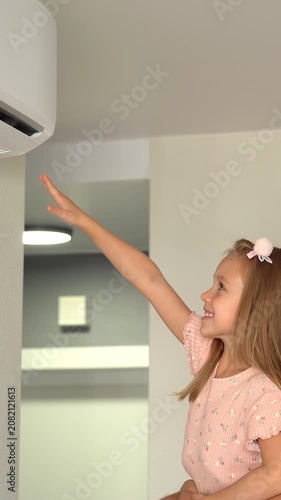 Close up of happy family father and little daughter fun turn on air conditioner using remote control
