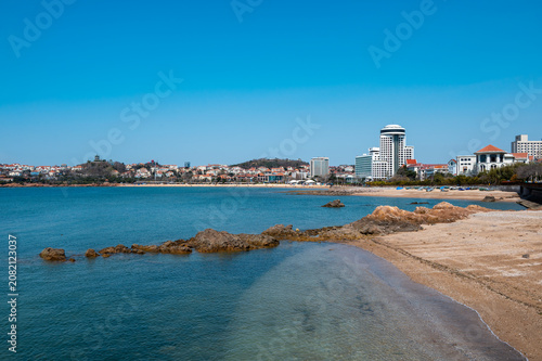 Canvas Print Qingdao Beach Shoreline with Rocks and City Buildings in Background, China