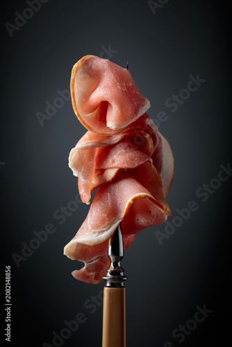 Raw fresh smoked pork bacon slices on a fork.