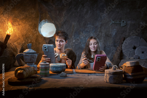Prehistoric Couple Using Smartphones at Breakfast