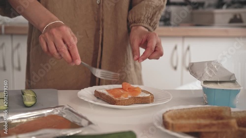 In a kitchen, a person prepares breakfast by spreading butter and jam on toast. They take slices of bread and make a simple meal to start the day.
