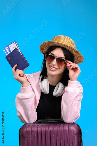 Foto Smiling young woman wearing sunglasses holding passport and boarding pass with s