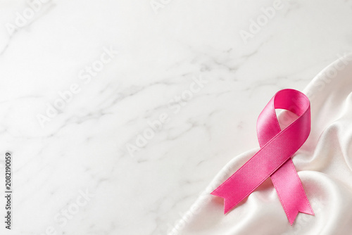Laço de cetim rosa sobre fundo de mármore branco com amplo espaço para texto - Conceito de conscientização sobre o câncer de mama, cuidado e prevenção.