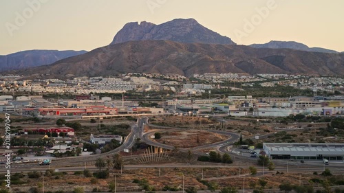 The city shows roads winding through the landscape with buildings and mountains in the background during dusk. The changing light highlights the scenery.