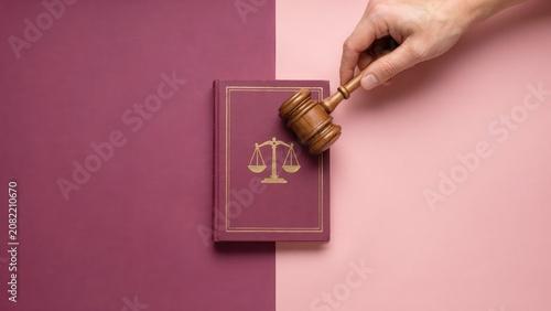 A hand holds a gavel over a law book on a pink and purple background