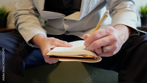 Obraz na plátně Middle aged candidate anxiously reviews handwritten notes in a leather notebook