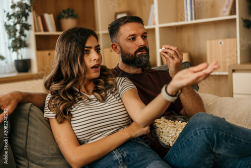 Valokuva Young couple watching thrilling movie while eating popcorn