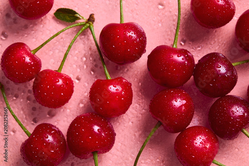 Фотография Fresh sweet cherries with water droplets on a pink background