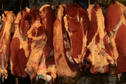 Fotografía Row of fresh raw beef cuts hanging on butcher hooks with butchery slaughterhouse