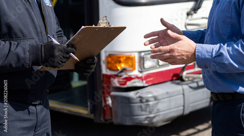 Traffic safety officer interviewing a bus driver and documenting a commercial vehicle collision beside a damaged bus for accident investigation and insurance claim
